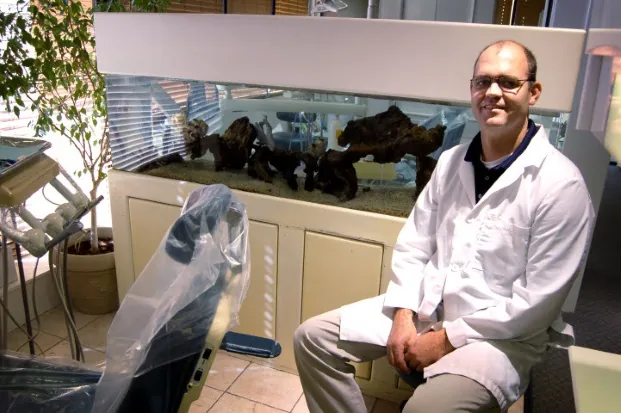 Dr. Matthews seated beside the aquarium in the treatment room